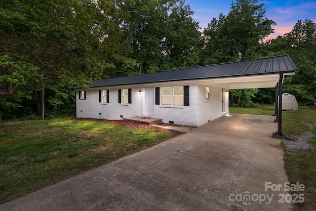 ranch-style home with crawl space, driveway, brick siding, a lawn, and metal roof