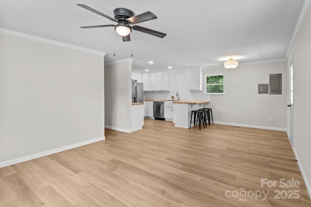 unfurnished living room with crown molding, a ceiling fan, a sink, light wood finished floors, and baseboards