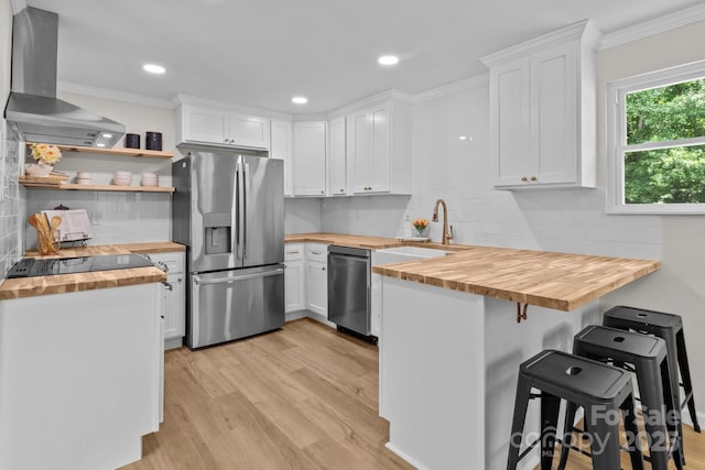 kitchen with wooden counters, stainless steel appliances, ventilation hood, a sink, and ornamental molding