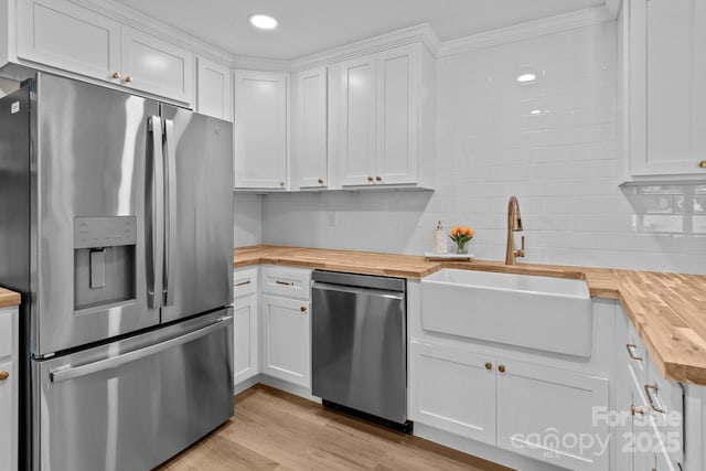kitchen featuring wood counters, appliances with stainless steel finishes, a sink, white cabinetry, and light wood-style flooring