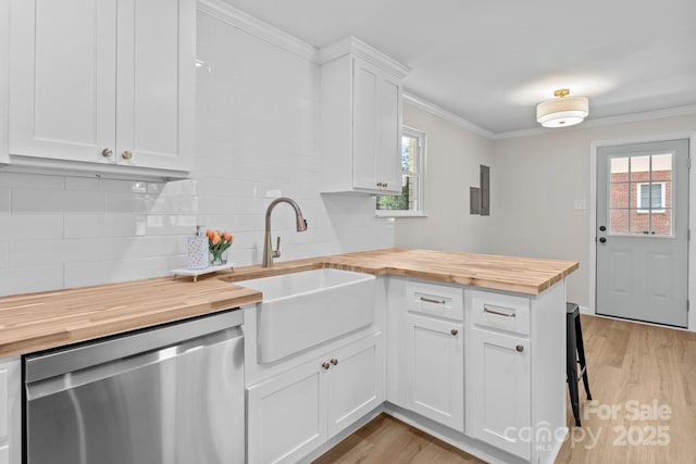 kitchen with wooden counters, dishwasher, a sink, a peninsula, and backsplash