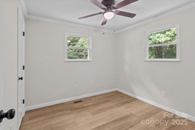 spare room with light wood finished floors, baseboards, crown molding, and a ceiling fan