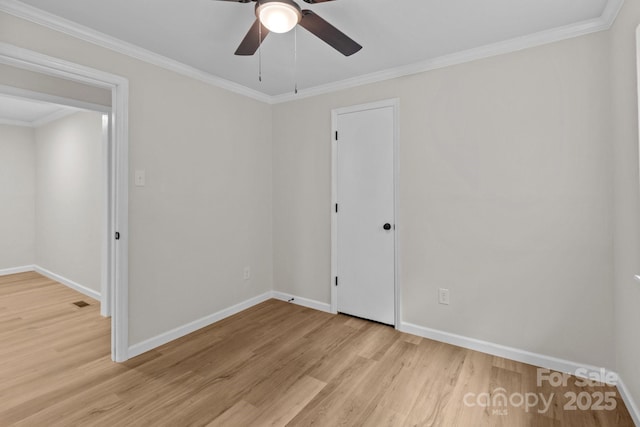 spare room featuring light wood-type flooring, baseboards, ceiling fan, and crown molding
