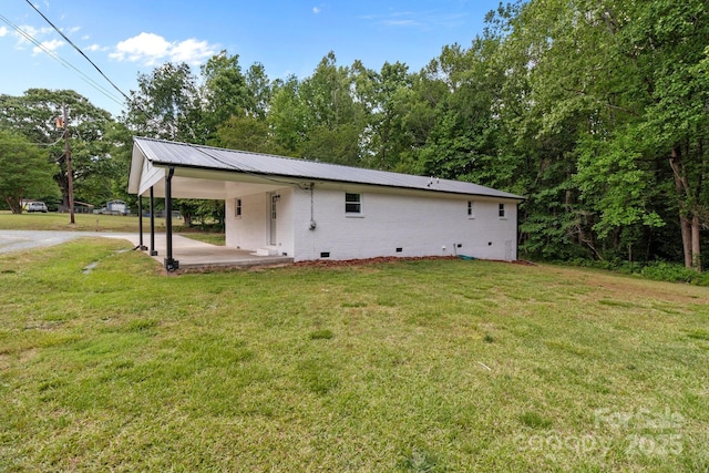 rear view of property featuring crawl space, a carport, a lawn, metal roof, and driveway