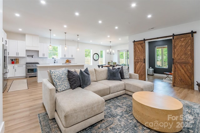 living area featuring a barn door, light wood-type flooring, and recessed lighting