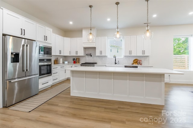 kitchen with stainless steel appliances, a sink, light countertops, light wood-style flooring, and recessed lighting