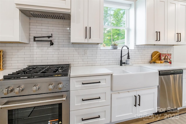 kitchen featuring stainless steel appliances, a sink, light countertops, white cabinets, and backsplash