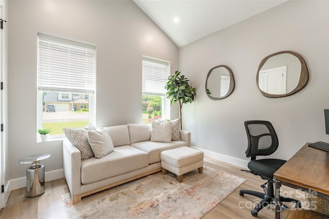 home office with light wood-style floors, baseboards, and high vaulted ceiling