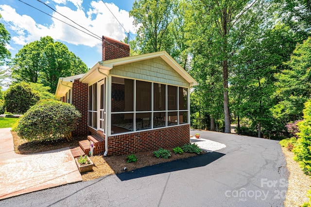 view of property exterior with a chimney and a sunroom