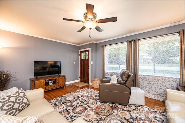 living area featuring wood finished floors, ornamental molding, a ceiling fan, and baseboards