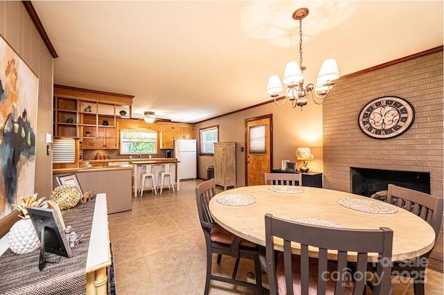 dining room featuring crown molding, a brick fireplace, a chandelier, and light tile patterned floors