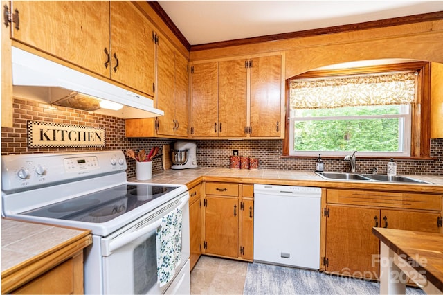 kitchen featuring white appliances, under cabinet range hood, a sink, tasteful backsplash, and tile countertops