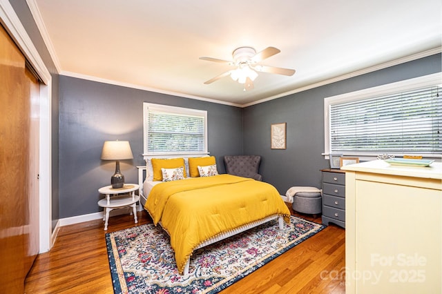 bedroom featuring wood finished floors, crown molding, a closet, a ceiling fan, and baseboards
