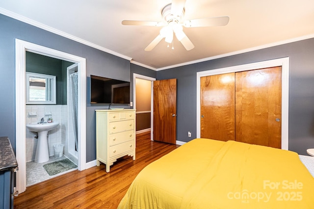 bedroom with wood finished floors, a sink, a closet, crown molding, and a ceiling fan