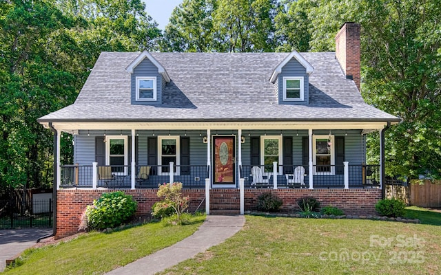 view of front facade with a porch, a chimney, and roof with shingles