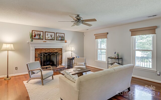 living area featuring healthy amount of natural light, wood finished floors, ceiling fan, and a textured ceiling