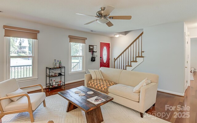 living area featuring wood finished floors, ceiling fan, and baseboards