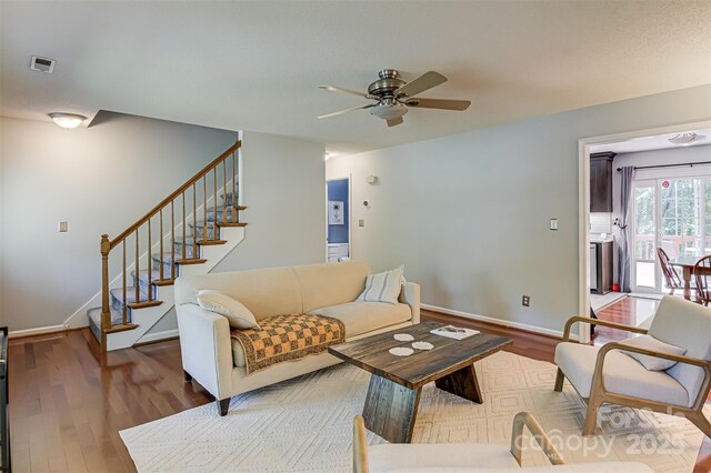 living room with ceiling fan, wood finished floors, stairway, and baseboards