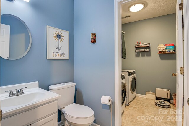 bathroom with washing machine and dryer, toilet, and vanity