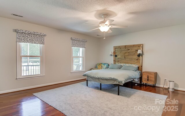 bedroom featuring dark wood finished floors, baseboards, ceiling fan, and a textured ceiling