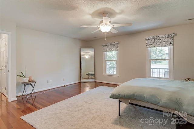 bedroom with wood finished floors, baseboards, a textured ceiling, and ceiling fan