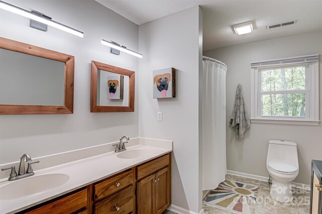 full bathroom featuring toilet, double vanity, and baseboards