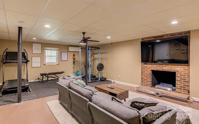 living room featuring a fireplace, recessed lighting, concrete floors, baseboards, and a paneled ceiling