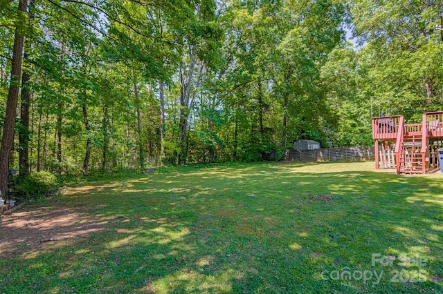 view of green lawn featuring a wooden deck and stairway