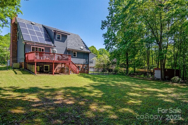 back of house with stairway, a deck, solar panels, a chimney, and an outbuilding