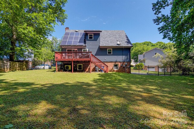rear view of house featuring stairway, a chimney, a wooden deck, solar panels, and brick siding