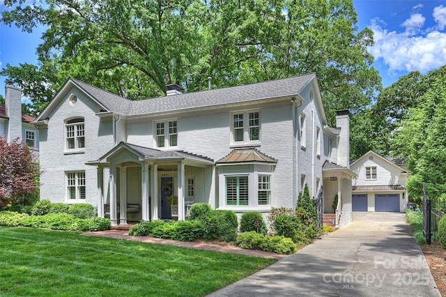 view of front of property featuring a chimney, an outdoor structure, a garage, and a front lawn