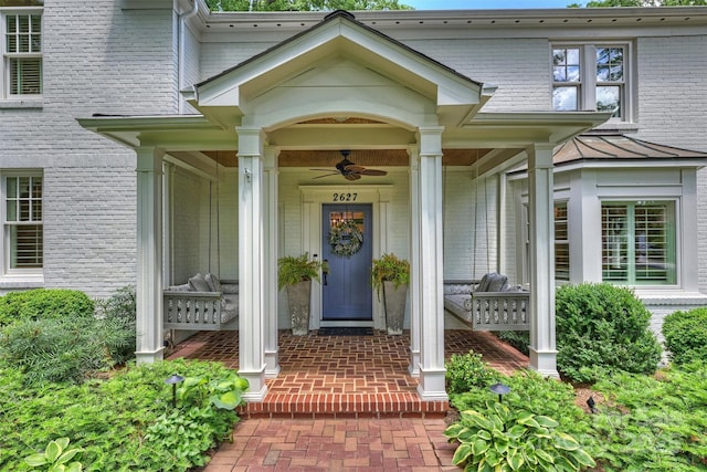 entrance to property with a ceiling fan, brick siding, and covered porch