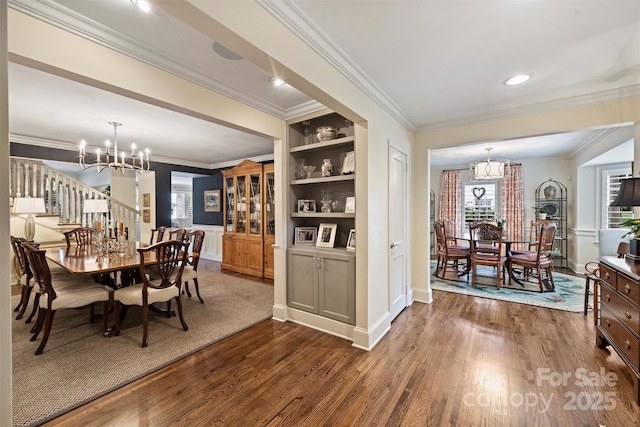 dining room with a chandelier, dark wood-style floors, ornamental molding, baseboards, and built in features