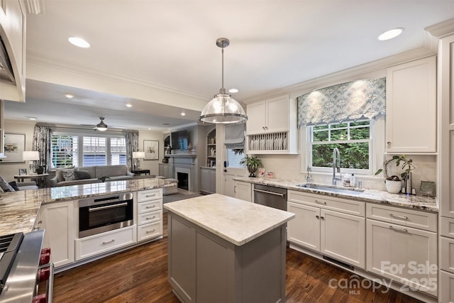 kitchen with a sink, open floor plan, appliances with stainless steel finishes, healthy amount of natural light, and crown molding