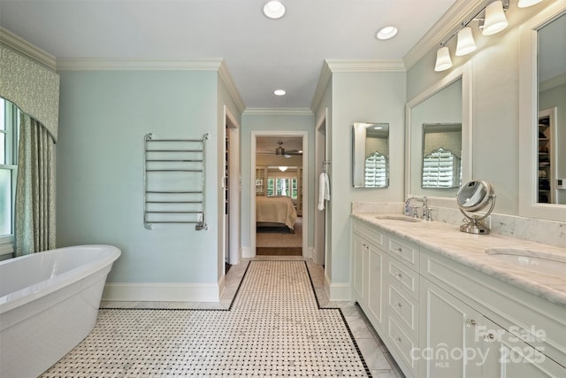 ensuite bathroom featuring ornamental molding, double vanity, recessed lighting, a freestanding tub, and baseboards