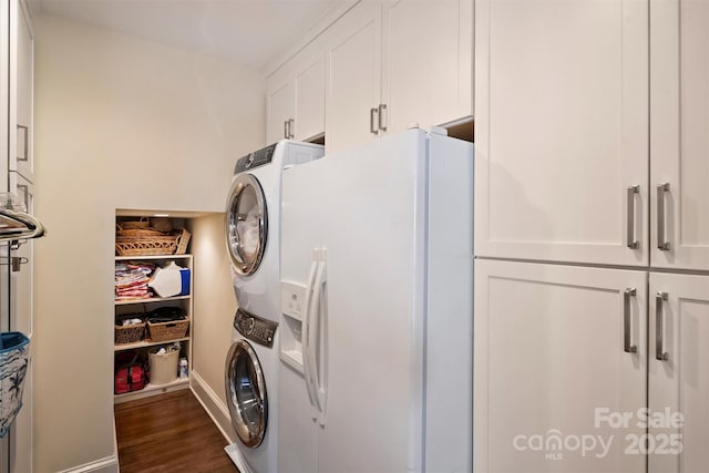 clothes washing area featuring cabinet space, stacked washer and clothes dryer, dark wood-style flooring, and baseboards