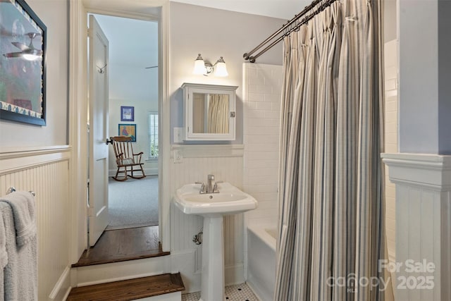 bathroom featuring a wainscoted wall, shower / bath combo, and a sink