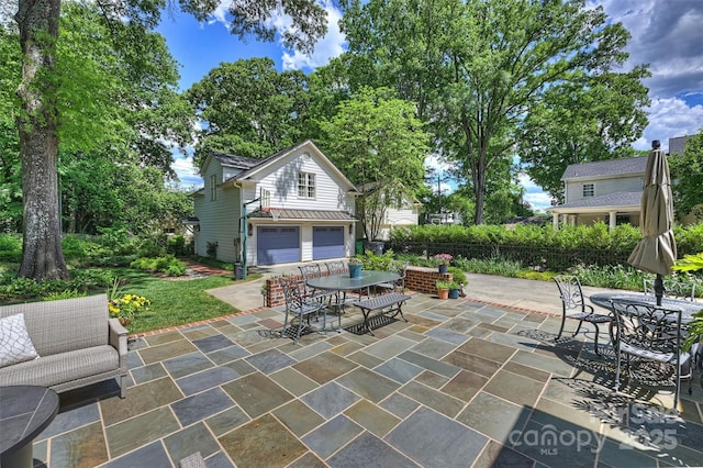 view of patio / terrace with outdoor dining area and an attached garage