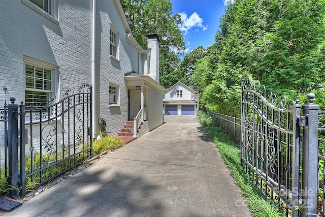 view of side of home featuring brick siding, a detached garage, a gate, and an outdoor structure