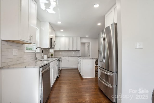 kitchen featuring stainless steel appliances, a sink, white cabinetry, decorative backsplash, and recessed lighting