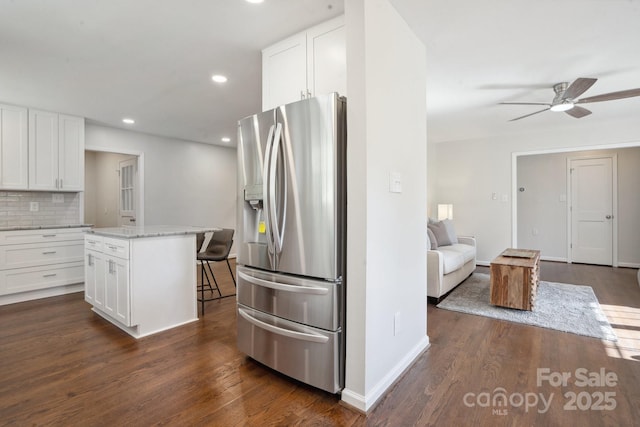 kitchen featuring stainless steel fridge, a kitchen bar, ceiling fan, white cabinetry, and a kitchen island