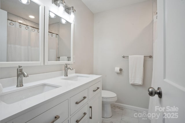 bathroom featuring marble finish flooring, baseboards, toilet, and double vanity