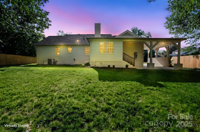 back of house at dusk featuring a chimney, central AC unit, crawl space, and a patio