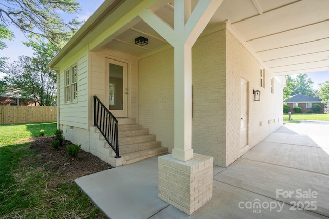 doorway to property featuring fence, crawl space, and brick siding