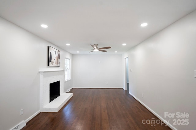 unfurnished living room with a ceiling fan, dark wood-type flooring, baseboards, recessed lighting, and a fireplace