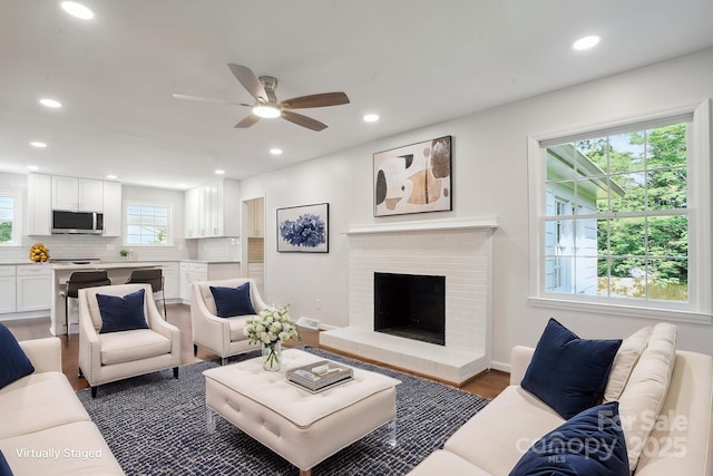 living room with recessed lighting, ceiling fan, wood finished floors, and a brick fireplace
