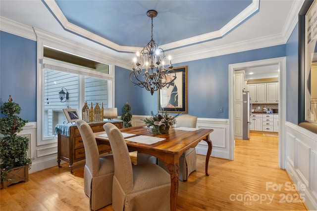 20017 Bragg, Chapel Hill, NC 27517 - dining space with a chandelier, a raised ceiling, light wood-style floors, a decorative wall, and a wainscoted wall