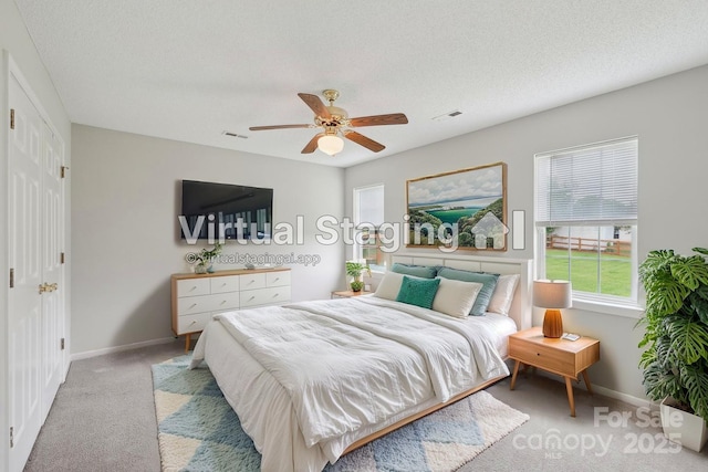 bedroom featuring carpet, multiple windows, baseboards, a ceiling fan, and a textured ceiling