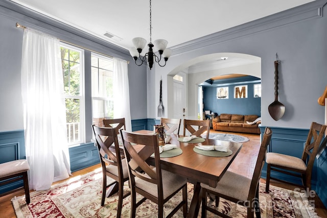 14940 Carbert Ln, Huntersville, NC 28078 - dining space featuring a wainscoted wall, arched walkways, crown molding, a decorative wall, and a chandelier
