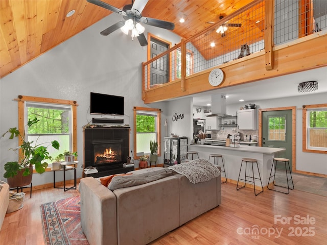 416 Secluded Cv, Waynesville, NC 28785 - living area with wood ceiling, high vaulted ceiling, a tile fireplace, a ceiling fan, and light wood-type flooring